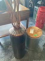 Image showing tall copper vase with ribbed design and natural decorative twigs inside beside galvanized can with wooden lid.