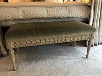 Front view of bench showing full length upholstered seat and carved apron