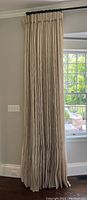 Full-length view of left curtain panel hanging from rod
