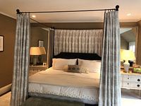 Front view of four-poster canopy bed with drapes drawn and bedding in place