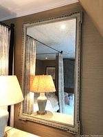 Full front view of rectangular mirror reflecting room and lamp.