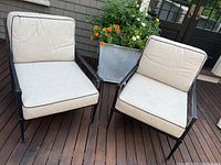 Both outdoor armchairs side by side on wooden deck with planter behind