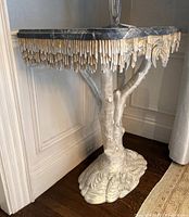 Single console table showing black marble top and sculpted tree-trunk base