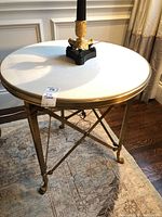 Front view of round limestone top on brass frame with table lamp