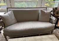 Full front view of sofa showing curved back, arms, upholstery and frame finish