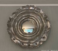 Front view of entire round mirror showing concentric ruffled metal frame and central mirror