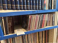 Photo showing a shelf with musical CDs in jewel cases closely packed, behind them are vinyl records with titles Olive Beaupre Miller on spines.