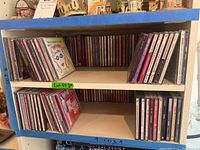 Two shelves of jewel case CDs showing front and back stacks