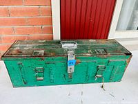 Green industrial metal toolbox with hinged lid, front latch and top handle, paint chipped and rusted
