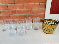 Group photo of the ice bucket and 10 glasses showing the gold and green patterned Culver ice bucket alongside rectangular and round etched glasses.
