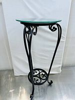 Full view of round glass top with wrought iron curled legs and base
