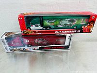 Photo of two NASCAR diecast tractor-trailer trucks in original packaging. Upper is green Dale Earnhardt Jr. #88 with Amp Mountain Dew, lower is red/white Tony Stewart #14 with Old Spice.