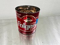 Side view of the Folgers Mountain Grown coffee can filled with copper pennies to near top.