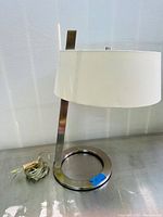 Front side view of the Sonneman Lighting Lina table lamp showing circular base and vertical arm with off-white drum shade.