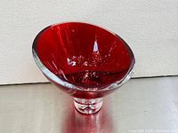 Front facing view of a deep ruby red thick glass bowl on a clear pedestal with a floating bubble inside.