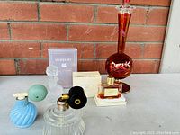Full view of all perfume bottles and items showing the large decorative red bottle, Dana Joy perfume bottle, and smaller assorted bottles with atomizers and lids.