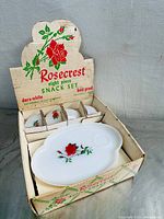 Original boxed set showing four white snack plates with red rose design inside the box with four matching cups.