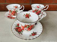 Photo of three Royal Albert Centennial Rose fine bone china tea cups and saucers set, showing the floral design and gold trim.