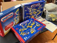 Three boxed Meccano Erector metal construction sets including a Ferris wheel set and others with various models depicted on the boxes.