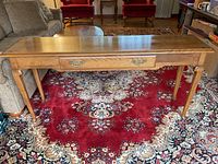 Front view of the full Ethan Allen console table showing the drawer and tapered legs on a red patterned carpet.