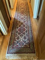 Full length of wool rug runner laid in hallway showing floral pattern and fringe.