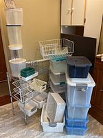 Full view of 3-shelf stainless steel rack with stacked plastic containers and organizers around it.