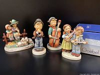 Four Goebel Hummel music themed figurines displayed together, showing details and scale.