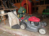 Three quarter view of mower with leaf bag and red gas can behind it