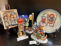 Four Hummel figurines and one Schmid Berta Hummel Christmas plate displayed together showing details and original boxes.