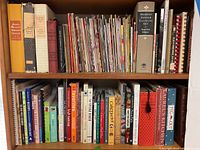 Full shelf view showing a wide range of cooking books of varying sizes and conditions, including vintage editions.