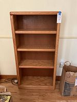 Full view of the oak book case showing three shelves inside and natural oak grain exterior.
