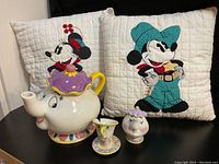 Overview of the lot showing Mrs. Potts teapot, mini Mrs. Potts and Chip figures, and two Disney-themed throw pillows of Minnie and Mickey Mouse.