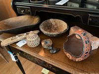 Full view of lot on wood table, showing large Treeware USA bowl, Peruvian handpainted gourd basket, hand-turned wood bowl, woven basket, polished stone, and carved wood duck.