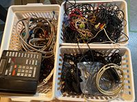 Three white plastic bins filled with assorted electronic cables and a black vintage corded phone