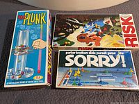 Photo showing boxes of Kerplunk, Risk, and Sorry board games together.