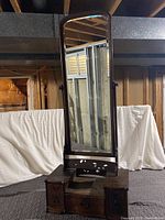 Full view of the antique Japanese wooden standing mirror showing beveled glass and drawer base