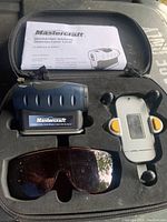 Laser level and accessories inside carrying case, including user manual, holder, and glasses.