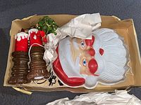 Photo of vintage Christmas decorations including large Santa mask, two electric candles, and artificial mistletoe in a box.