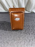 Closed brown leather case front view with Yashica embossing and metal badge
