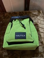 Front view of lime green Nautica backpack with black leather trim and Nautica logo patch on front pocket.