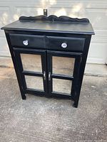 Front view of the black buffet cabinet showing crystal knob drawers and mirrored doors