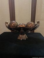 Front view of decorative centerpiece bowl on pedestal base filled with three amber orbs