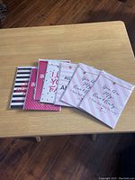 Seven packaged heart pendant necklaces on gift cards laid out on a wooden table, showing various card designs and messages.
