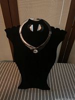 Photo of the Monet choker necklace displayed on black velvet stand showing silver and black colors and curved design.