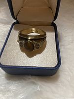 Front angled view of the 14k gold men's ring with tiger's eye center and clear side stones in ring box.
