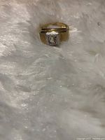 Front view of 14kt men's gold ring with square bezel center stone on white fur background showcasing stone and gold band.