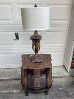 Wicker end table with ornate curved legs and three drawers, showing broken handles and signs of wear