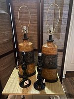 Two tall ceramic lamps approximately 31 inches tall with brown and beige coloring and detailed ceramic patterns, placed on a table next to two shorter black lamps with rounded bases.