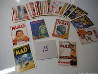 Full spread view showing multiple Mad Magazine trading cards laid out in a fan shape, with varied cartoon and satirical artwork.