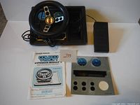 Overview of the Coleco Vision Expansion Module lot items including steering wheel, gas pedal, expansion module base unit, and owner's manual